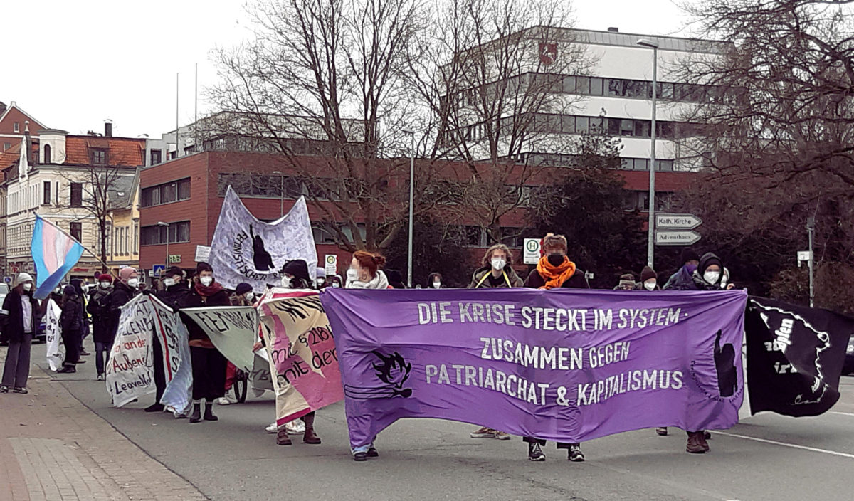 7.3.2021 Feministische Demo in Lüneburg mit violettem Frontbanner: " Die Krise steckt im System - Zusammen gegen Patriachat und Kapitalismus