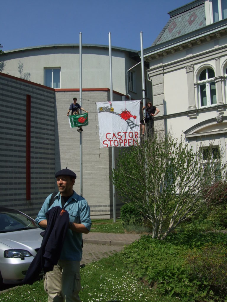 2 Menschen auf Fahnenmasten vorm AG Greifswald mit Banner "castor stoppen"