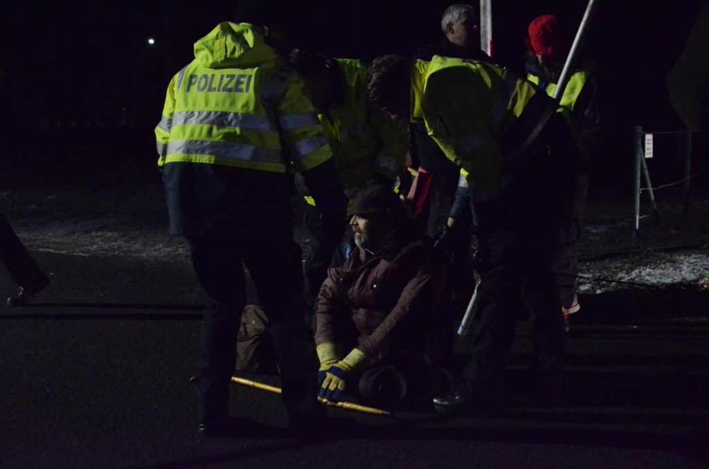 Karsten sitzt am Boden, Polizeisten haben ihn umstellt udn scheinen sich an ihm zu wenden