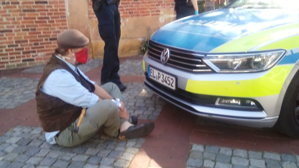 Karsten sitzt vor einem Polizeiauto