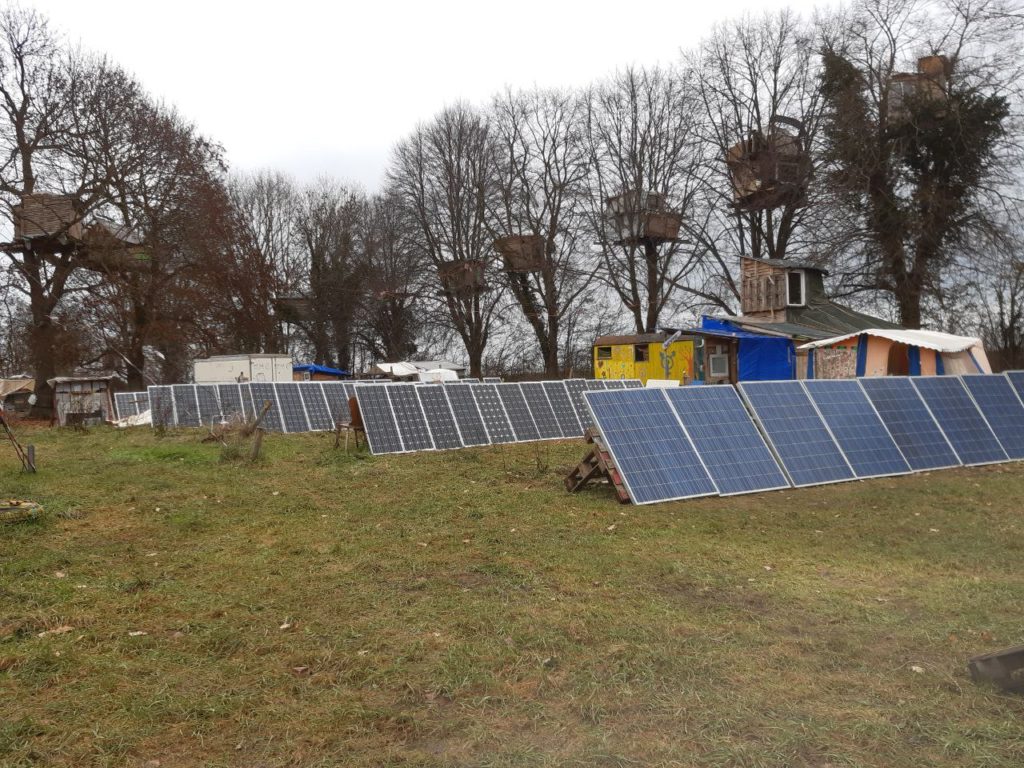 Solaranlage auf einer Wiese, Baumhäuser.