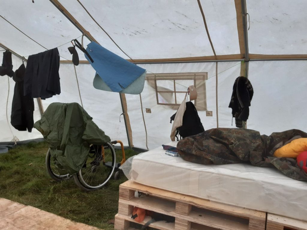 Bett und Rollstuhl in einem roßen Zelt